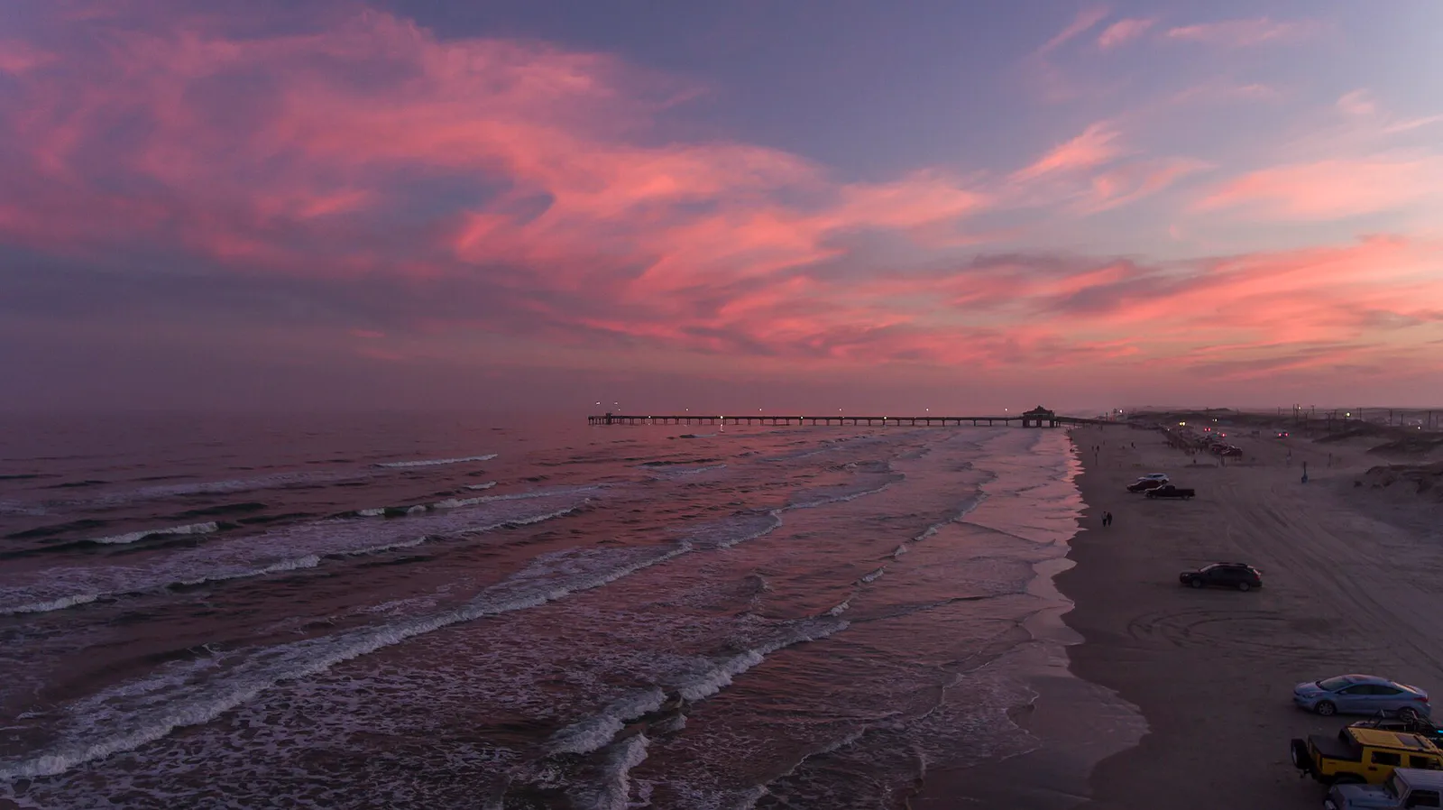 An aerial view of South Padre Island with people parked and driving on the beach at sunset, Texas